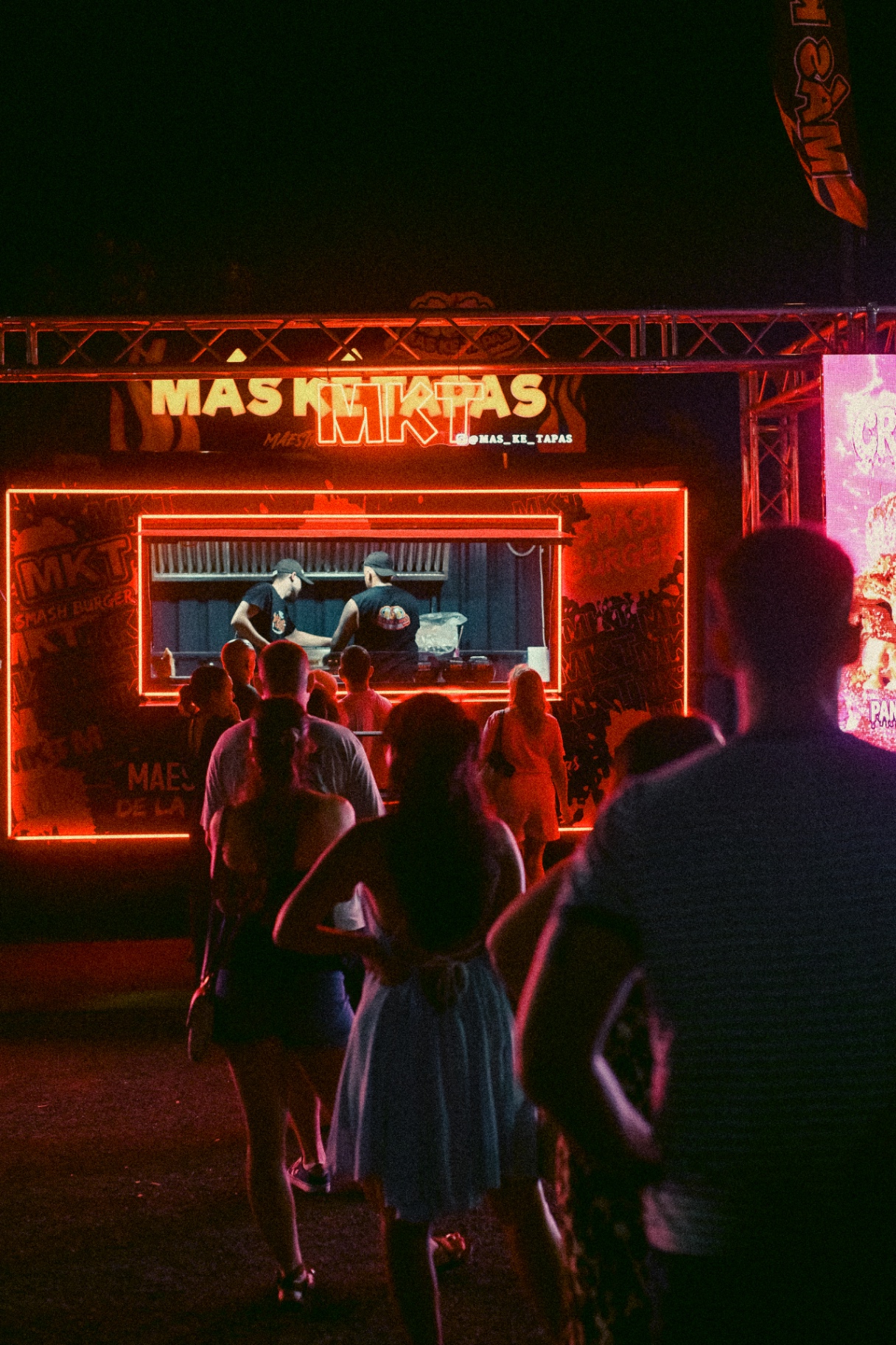 Público haciendo cola frente a la ventanilla de la foodtruck MÁS KÉ TAPAS mientras el equipo cocina